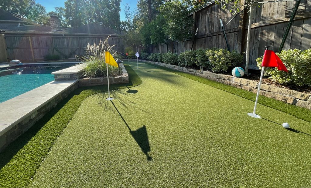 Backyard golf green next to residential pool area 