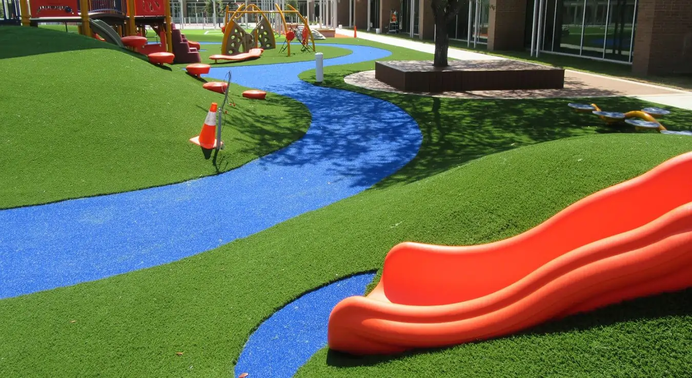 Orange slide installed on artificial playground grass
