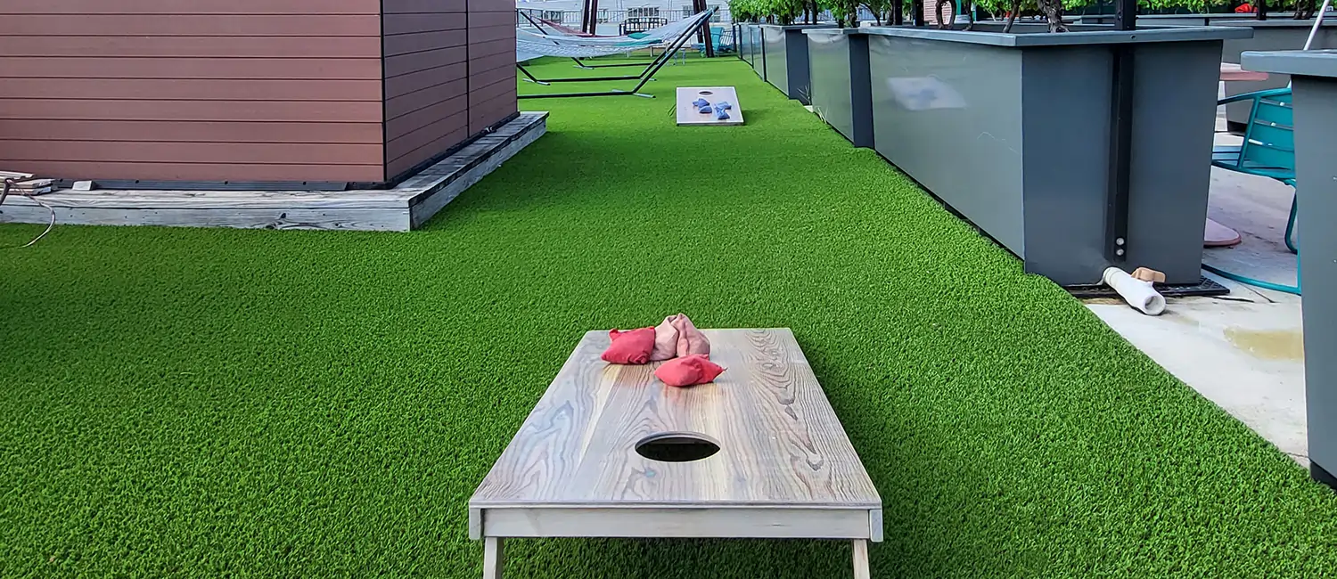 cornhole game on bay area artificial grass rooftop installation